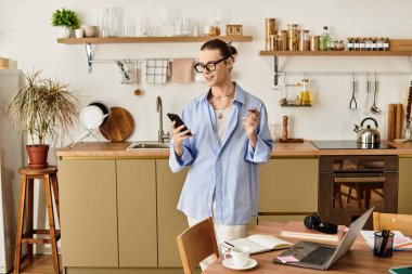 Genç bir adam şık bir mutfakta, telefonunu sıcak dekorun içinde kontrol ediyor..