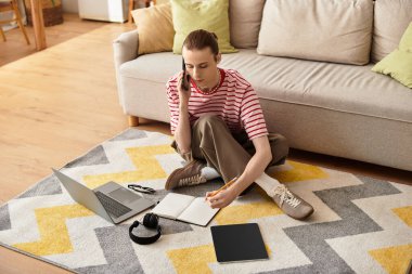 Genç adam telefonda konuşurken ilham alıyor ve rahat bir halının üzerinde defterine fikirler çiziyor..