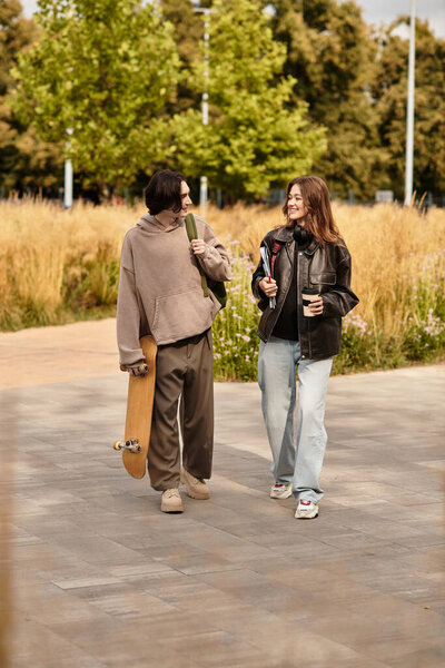 Loving couple walks hand in hand through a sunny park, sharing smiles and drinks together.