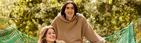 A young couple relaxes together in a hammock, enjoying their love and natures beauty nearby.