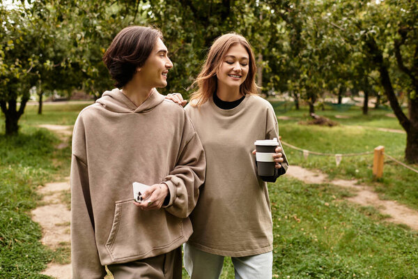 A loving couple walks hand in hand, laughing in a peaceful outdoor setting surrounded by trees.