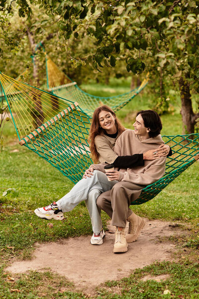 A loving couple sits in a hammock, sharing laughter and joy in a beautiful outdoor setting.