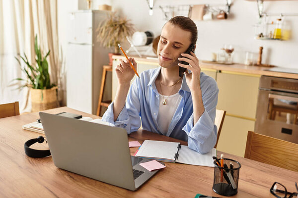 Young, feminine man engages in a productive work session at home while on the phone.