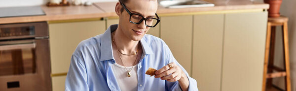 Молодой красивый мужчина с женственными чертами вкусов вкусный укус в современной обстановке кухни.