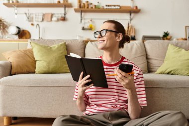 Zeki ve neşeli genç adam yere oturup defterine gülümseyerek bir şeyler yazıyor..