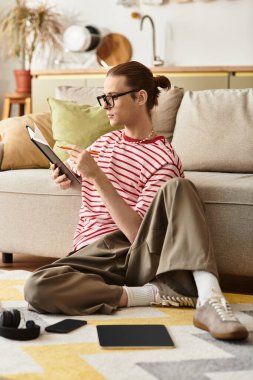 Genç ve yakışıklı bir adam, şık bir yaşam alanına gömülmüş, öylesine yerde oturuyor..