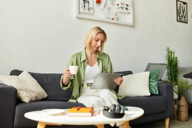 Bir kadın evinde kahve ve tabletle rahat bir atmosferin tadını çıkarıyor..