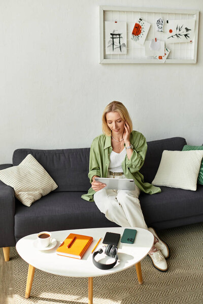 Relaxing in a warm home environment, a woman reads on her tablet, surrounded by cozy decor.