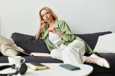 Rahat bir mekanda, rahat giyimli hoş bir kadın gününü bir defterle yansıtıyor..