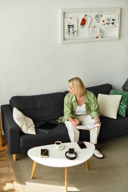 Sıcak ve davetkar bir sahne, rahat bir evde günlük giysiler içinde notlar yazan bir kadın..