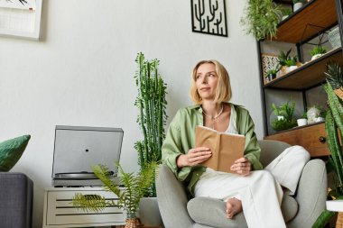 Evde dinlenen güzel bir kadın, yeşil bitkiler ve hoş dekorlarla çevrili bir kitap okuyor..