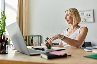 Sıradan giyinmiş hoş bir kadın masasında oturmuş, evinde yaratıcı bir işe dalmış..