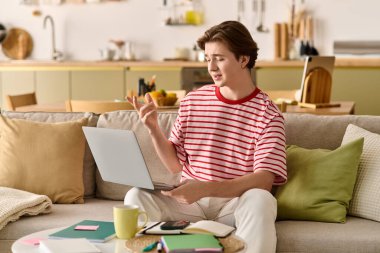 Genç bir adam, çevresindeki malzemelerle modern evinden uzaktan eğitim görüyor..