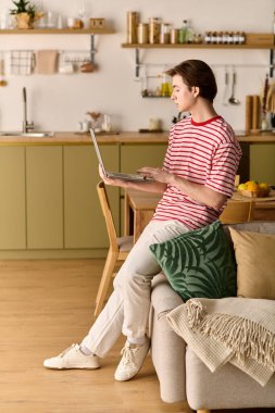 Genç bir adam konsantrasyonunu bozmadan, rahat dairesinden e-öğrenme ile meşgul oluyor..