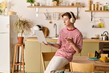 Genç bir adam bir masada oturuyor, modern dairesinde internetten çalışıyor, odaklanmış ve meşgul..