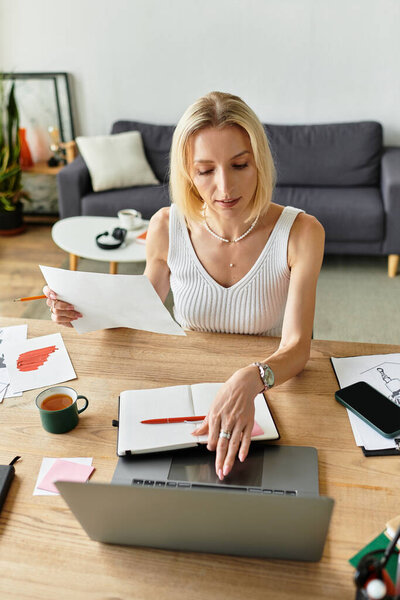 A woman works at home, surrounded by notes and coffee, enjoying her day.