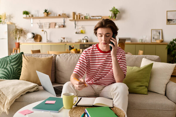 In a stylish apartment, a young man engages in online classes with notes and a laptop.
