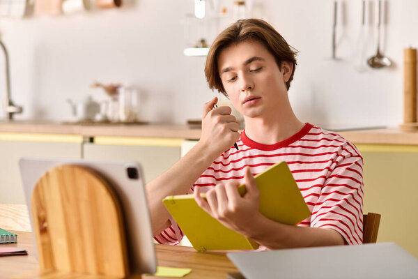 Сосредоточенный молодой человек учится в Интернете, делает заметки в яркой квартире, наполненной светом.