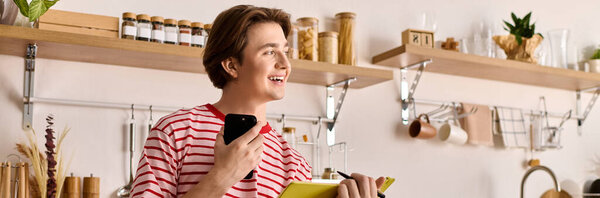 Молодой человек учится дома, используя свой ноутбук и делая заметки в яркой, современной квартире, баннер