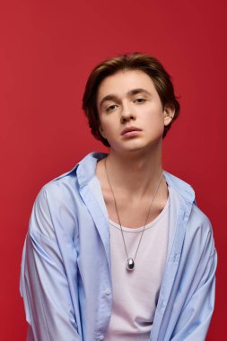 Modayı takip eden genç bir adam, kendine güvenen mavi bir gömlek içinde, modern yetenekler saçarak poz veriyor..