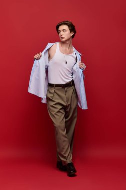 Modayı takip eden genç adam, kendine güvenen bir poz veriyor. Pantolon ve mavi gömlekli.