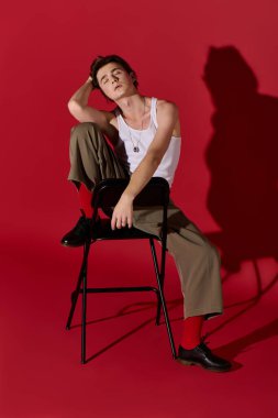 Modayı takip eden genç bir adam şık bir pantolon ve askılı bluzla poz veriyor. Modern modanın vücut bulmuş hâli..