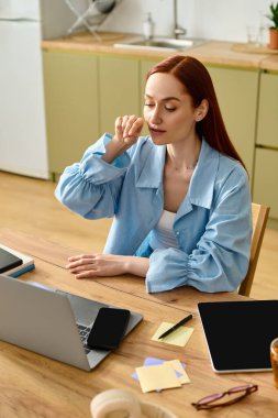 A woman with red hair teaches language online from her home office using a laptop.