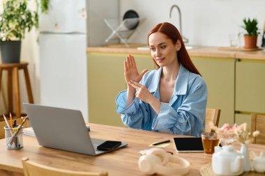 A woman with red hair teaches language skills online, smiling and interacting with her students.
