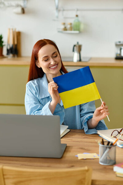 A woman with red hair teaches a language class online, showcasing a colorful flag proudly.
