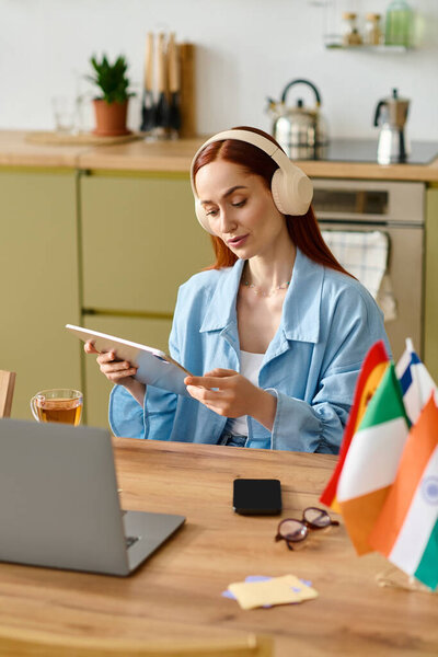 A woman with red hair teaches language lessons at home using her laptop, creating a warm atmosphere.