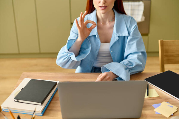 A dedicated language teacher with vibrant red hair conducts an online lesson from her home office.