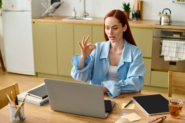 A woman with red hair actively teaches language online from her cozy kitchen workspace.