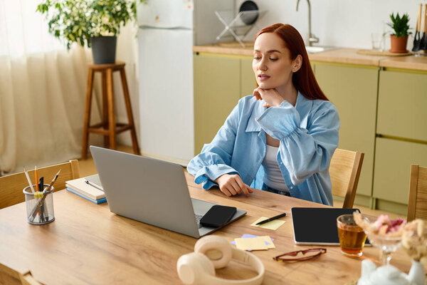A woman with red hair teaches languages online while sitting at her desk at home.