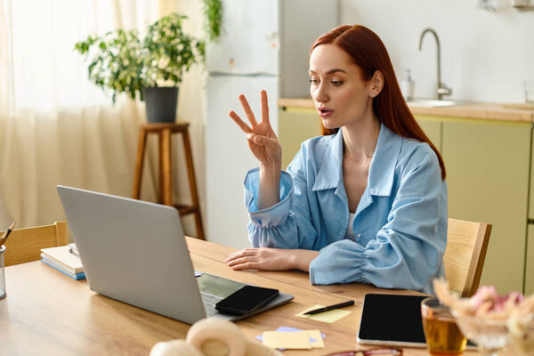A red-haired teacher is leading an online lesson from her home workspace.