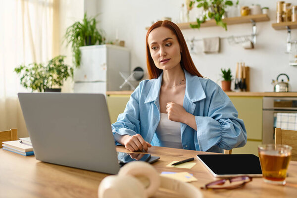 A woman with red hair teaches languages online, using her laptop in a bright, inviting home setting.