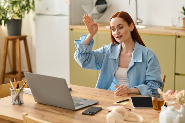 A woman with red hair teaches a language class online from her cozy home workspace.