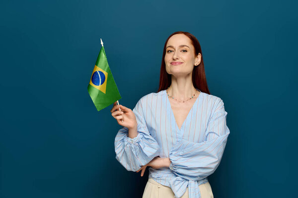 A language teacher stands confidently in a studio, proudly displaying a Brazilian flag.
