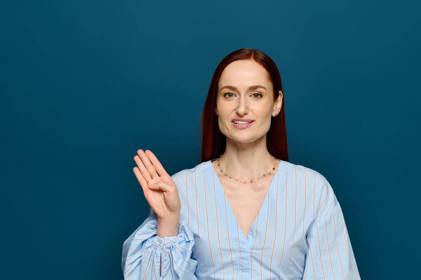A woman with red hair teaches sign language in a bright classroom setting.
