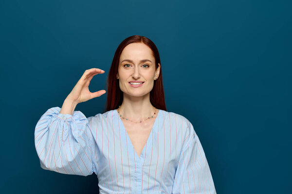 A red-haired woman teaches sign language against a blue backdrop to engage her students.