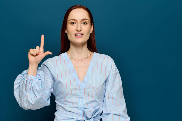 A woman with red hair teaches sign language, engaging students in a colorful setting.