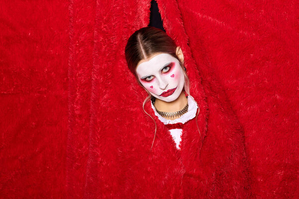 A striking young woman poses in a vibrant clown costume, ready for Halloween festivities.