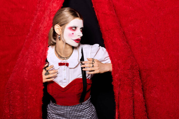 Young woman dressed in a striking Halloween costume, stepping through a vibrant red curtain.