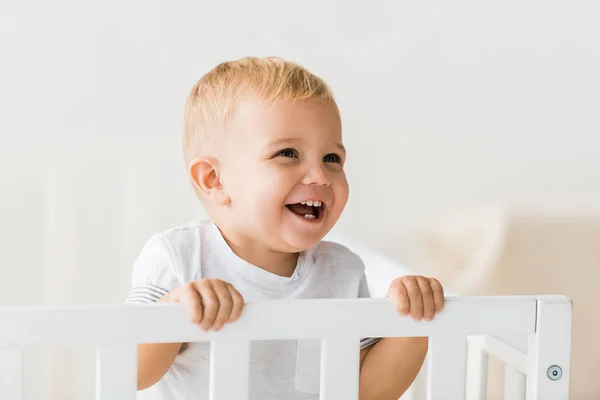 Joyeux bambin debout dans la crèche de bébé sur fond blanc — Photo de stock
