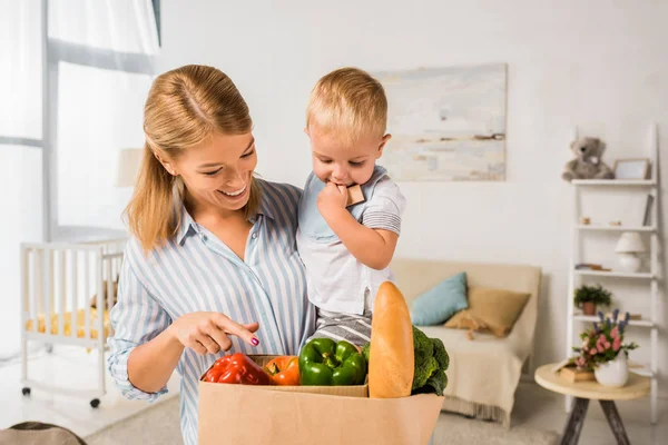 Усміхнена щаслива мати показує продукти синові — стокове фото