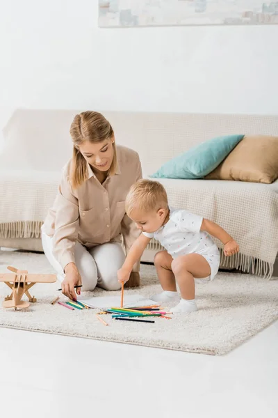 Happy mother and adorable toddler drawing together in nursery room — Stock Photo