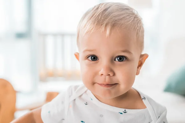 Gros plan de adorable tout-petit regardant la caméra dans la chambre d'enfant — Photo de stock