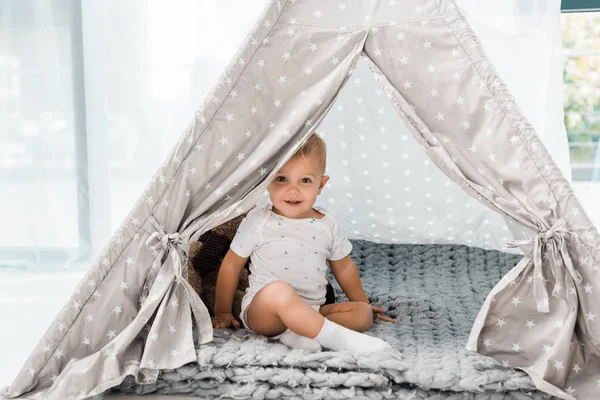 Sorrindo adorável criança sentada no bebê wigwam — Fotografia de Stock