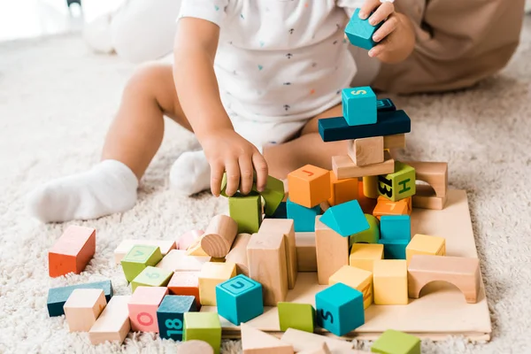 Abgeschnittene Ansicht eines entzückenden Kleinkindes, das mit bunten Würfeln spielt — Stockfoto