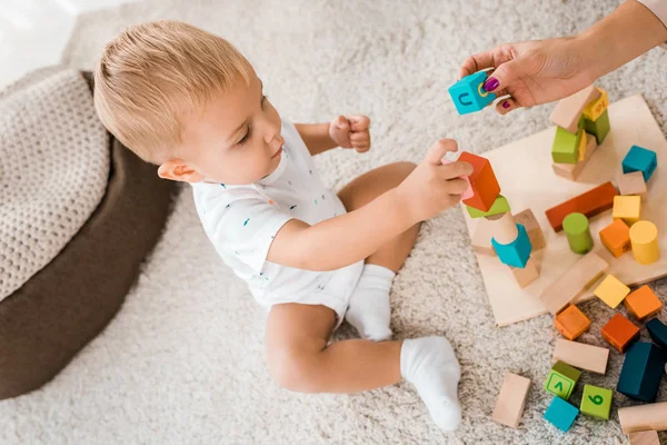 Ángulo de visión en adorable niño jugando con cubos de colores en la habitación de la guardería - foto de stock