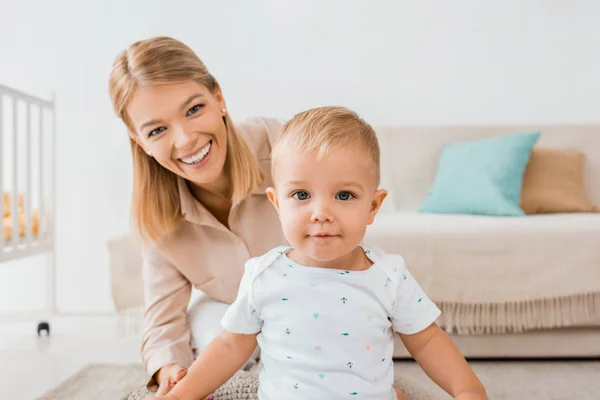 Adorabile bambino guardando la fotocamera con la madre nella stanza dei bambini — Foto stock